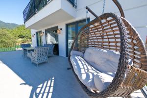 a wicker swing chair on a porch with a table at Oasis Family-Friendly Luxury Villa Hisaronu, Ovacik by Sunworld Villas Fethiye in Fethiye