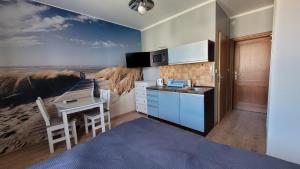 a kitchen with a painting of the beach on the wall at Amber in Mrzeżyno