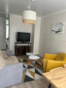 a living room with a yellow couch and a tv at Charmant appartement Grand Stade in Villeneuve d'Ascq
