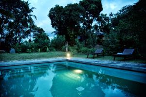 a swimming pool with two chairs sitting next to it at The Country House Chalets in Galle