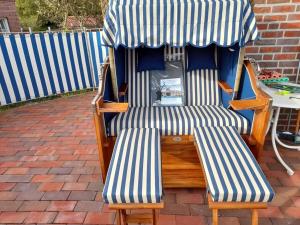 zwei Stühle unter einem Schirm auf einer Terrasse in der Unterkunft Nice holiday home near town centre in Juist