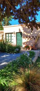 uma casa branca com uma porta verde e algumas plantas em Los Arcabuceros Posada Boutique em Tilcara