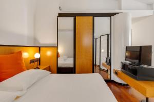 a bedroom with a white bed and a television at Hotel Ancora in Verbania