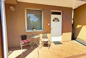 un patio con 2 sillas, una mesa y una puerta en Family Vendégház en Hajdúszoboszló