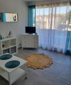 Una sala de estar con una mesa y una alfombra. en Très beau Studio Cosy à 500m de la Plage, en Gruissan