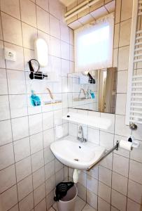 ein weißes Badezimmer mit einem Waschbecken und einem Spiegel in der Unterkunft Family Vendégház in Hajdúszoboszló