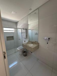 a bathroom with a sink and a toilet and a mirror at Pousada Villa D Manu in Penha