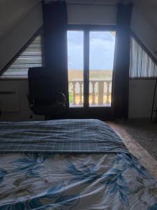 a bedroom with a bed and a chair and a window at BG Apartments in Somogyhatvan