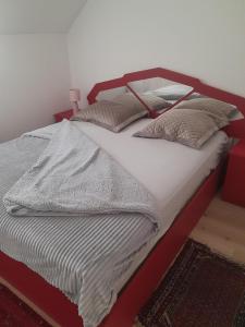 a bed with a red frame and pillows on it at 2 chambres adjacentes avec lit Queen size in Commugny