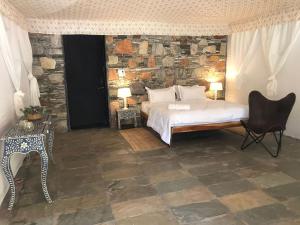1 dormitorio con cama y pared de piedra en The Chocolate Frog en Udaipur