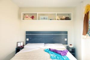 Schlafzimmer mit einem großen Bett mit blauem Kopfteil in der Unterkunft Campeggio la Mariposa in Alghero