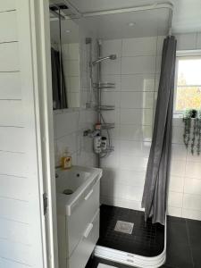 uma casa de banho branca com um lavatório e um chuveiro em White little house on the countryside, close to Stockholm em Vidja