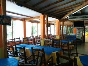 um restaurante com mesas e cadeiras azuis e janelas em Campeggio la Mariposa em Alghero