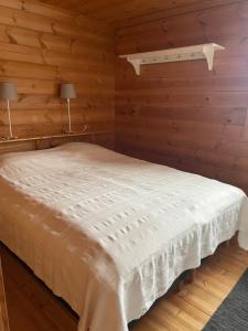a bedroom with a white bed with wooden walls at Yllästölli 2 A, Äkäslompolo in Kolari