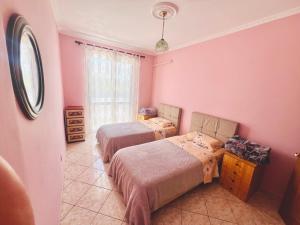 two beds in a room with pink walls at Lovely 3-bedroom rental unit in Durrës in Durrës