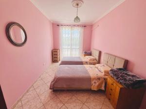 two beds in a room with pink walls and a mirror at Lovely 3-bedroom rental unit in Durrës in Durrës