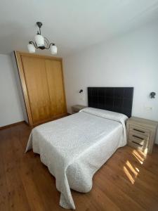 1 dormitorio con cama blanca y suelo de madera en Apartamento en Carreña de Cabrales, en Carreña