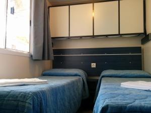 two twin beds in a room with a window at Campeggio la Mariposa in Alghero