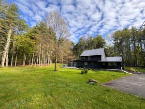 una casa negra en medio de un campo en Ginger House - Charming 3 bedroom cottage 4 min from Woodstock, en Woodstock