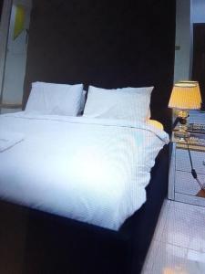 a bed with white sheets and pillows next to a lamp at Koko HOMES LEKKI PHASE 1 in Lagos