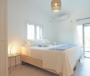 a white bedroom with a large bed and windows at Little Iremia in Kouspádes