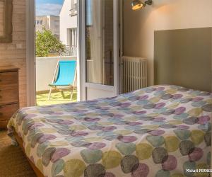 - une chambre avec un lit et un balcon avec une chaise dans l'établissement RÉF 344 - LARMOR-PLAGE Appartement centre bourg avec balcon plages et commodités à pied, à Larmor-Plage