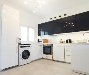 a kitchen with white cabinets and a washer and dryer at Little Iremia in Kouspádes
