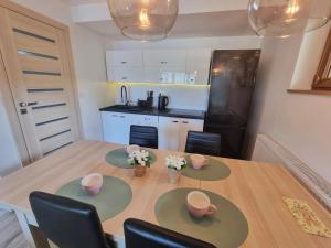 kuchnia z drewnianym stołem z krzesłami i jadalnią w obiekcie APARTAMENT Z POMOSTEM nad Jeziorem Czorsztyńskim w mieście Frydman