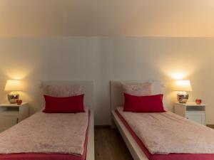 twee bedden in een kamer met rode kussens en lampen bij Ferienwohnung Elena in Tettnang