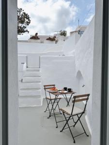 a small table and chairs on a balcony with white walls at as holiday caves in Mesaria