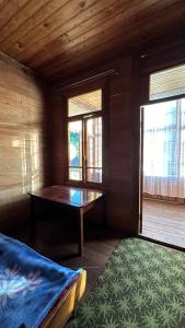 Habitación con 1 cama, 1 mesa y 2 ventanas en Wood House Gomi, en Ozurgetʼi