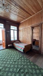 1 dormitorio con cama y alfombra verde en Wood House Gomi, en Ozurgetʼi