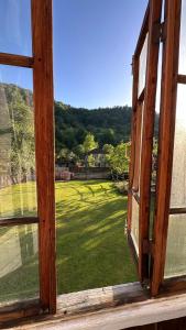 una ventana abierta con vistas a un campo de césped en Wood House Gomi, en Ozurgetʼi