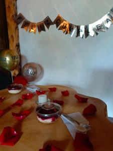 拉卡萊拉的住宿－Cabaña en la Calera BersaNina，一张桌子,上面有红玫瑰花瓣和蜡烛