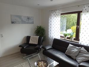 a living room with a black couch and a chair at Ferienwohnung Erftalblick in Hardheim