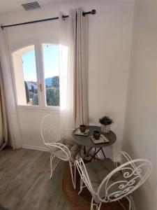 uma mesa e cadeiras num quarto com uma janela em Chambre climatisée entre mer et montagne, avec SDB et WC privatifs em Laroque-des-Albères