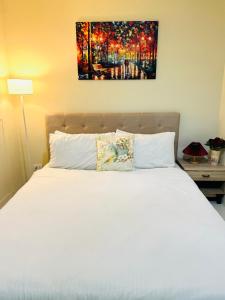 a bedroom with a white bed and a painting on the wall at PREMIUM CONDO AT BRENTHILL BAGUIO in Baguio