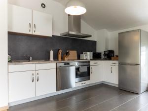 a kitchen with white cabinets and a stainless steel refrigerator at Ferienwohnung Elena in Tettnang