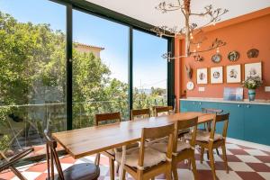 una sala da pranzo con tavolo e sedie in legno e ampie finestre di Chalet Futuro Terrace Sea View a Estoril