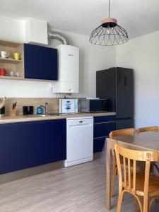 une cuisine avec des placards bleus et une table avec une salle à manger dans l'établissement Ker LN, à Saint-Nazaire