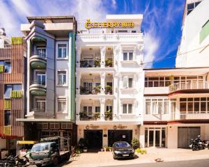 a white building with cars parked in front of it at CHERRY HOTEL in Da Lat