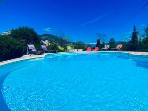 uma grande piscina de água azul com cadeiras em Villa Côte d'Azur piscine privée em La Gaude
