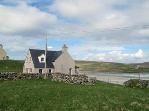 a white house on a hill with a stone wall at Airebroc House in Uig
