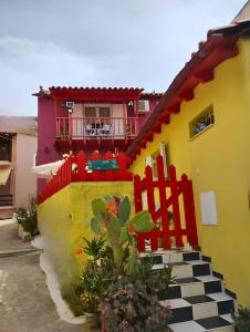 een geel huis met een rood hek en een huis bij "Wonderland" Nest Nafplio in Nafplio