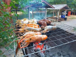 a bunch of meat and vegetables cooking on a grill at Adventure Point Resort By Sali in Kaeng Krachan