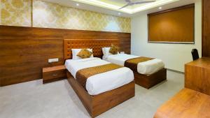 a bedroom with two beds and a large screen at Hotel Nova Pride in Rajkot