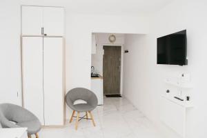 a white living room with two chairs and a tv at Saska Kępa Luxe Apartment in Warsaw