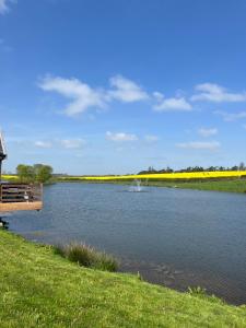 a river with a dock in the middle of a field at East Learmouth Lakeside Lodges - Larch Lodge in Cornhill-on-tweed