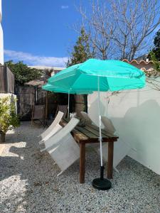 a picnic table with a blue umbrella and chairs at Villa L'Amiraute in Agde