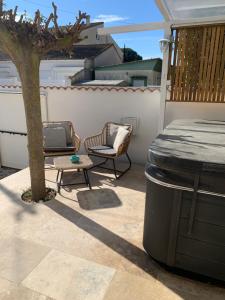 a patio with two chairs and a table and a tree at Villa L'Amiraute in Agde